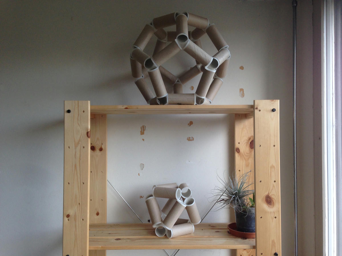 A dodecahedron and a octahedron made from toilet paper rolls on a shelf